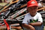 A young child sits in front of weapons handed in to RAMSI. Photo by AFP. 
