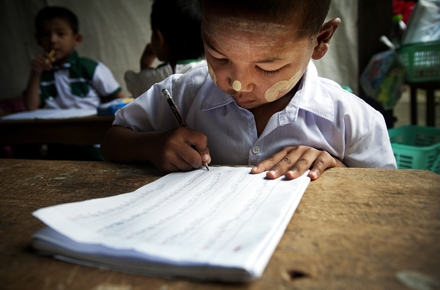 A young boy learns to write in a Burmese kindergarten class. Photo by UN Photo on flickr.